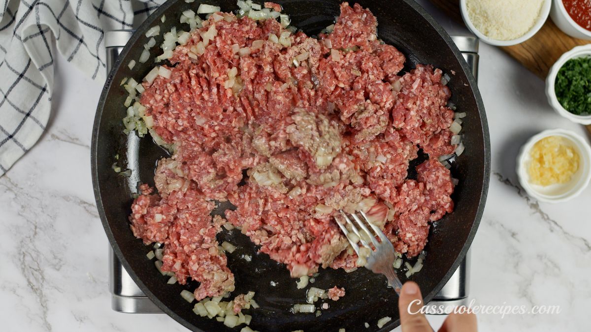 raw ground beef in skillet being cooked