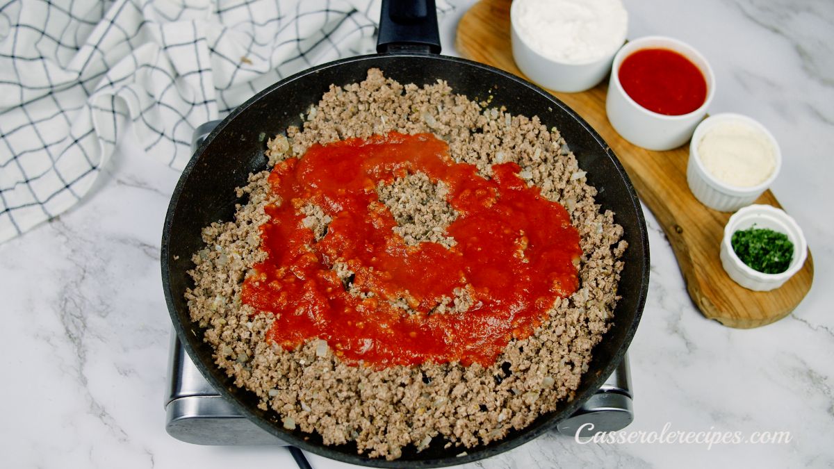 tomato sauce in black skillet of ground beef
