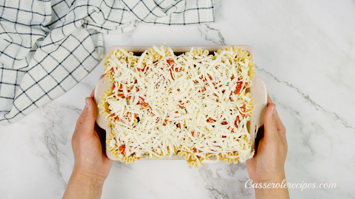 cheese on top of unbaked lasagna rolls in large white casserole dish
