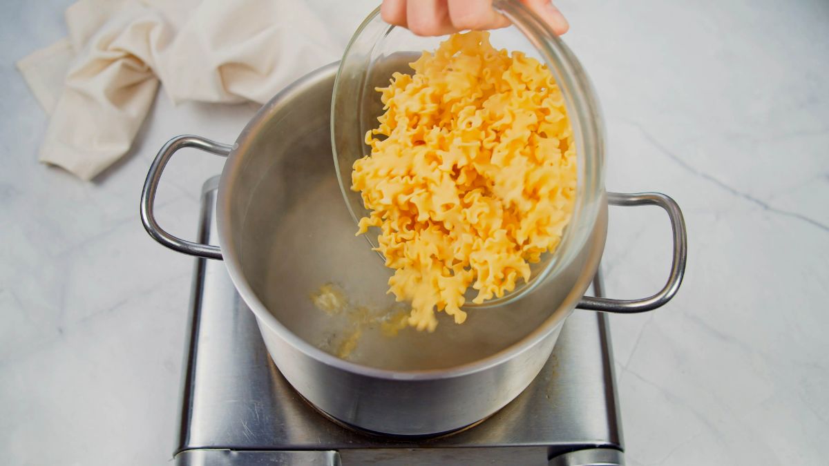 pasta being added to boiling water on hot plate