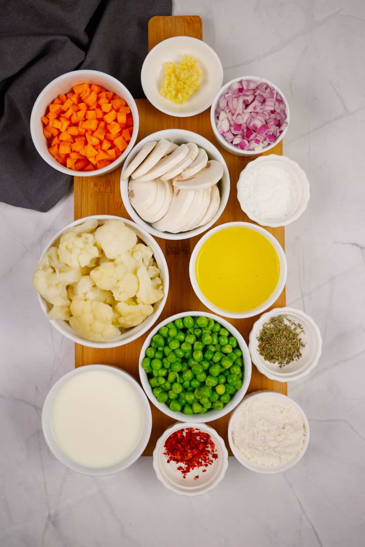 various sized white ramekins of vegetables and ingredients for making pot pie
