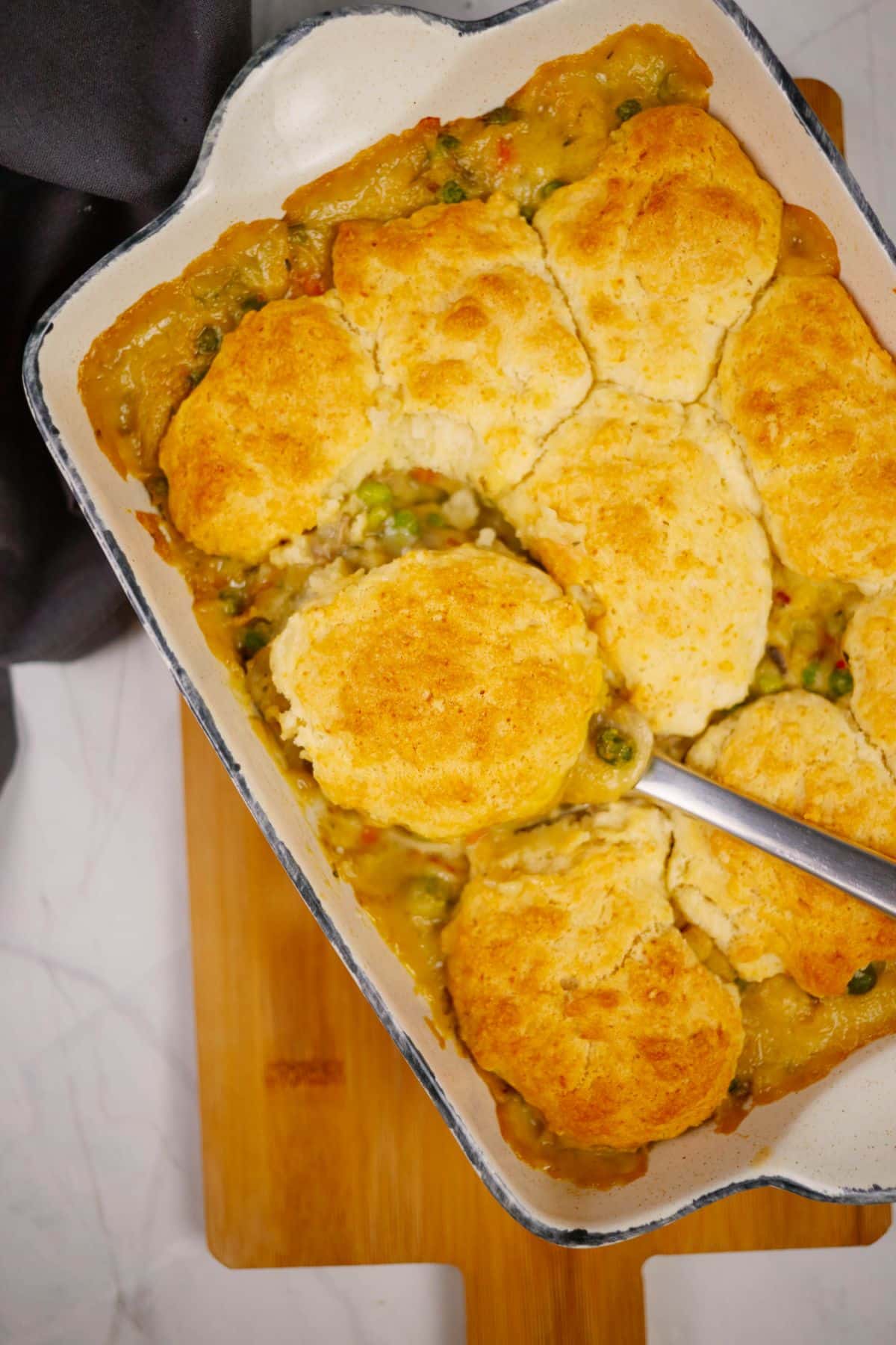white baking dish of vegetable pot pie casserole on top of wooden cutting board