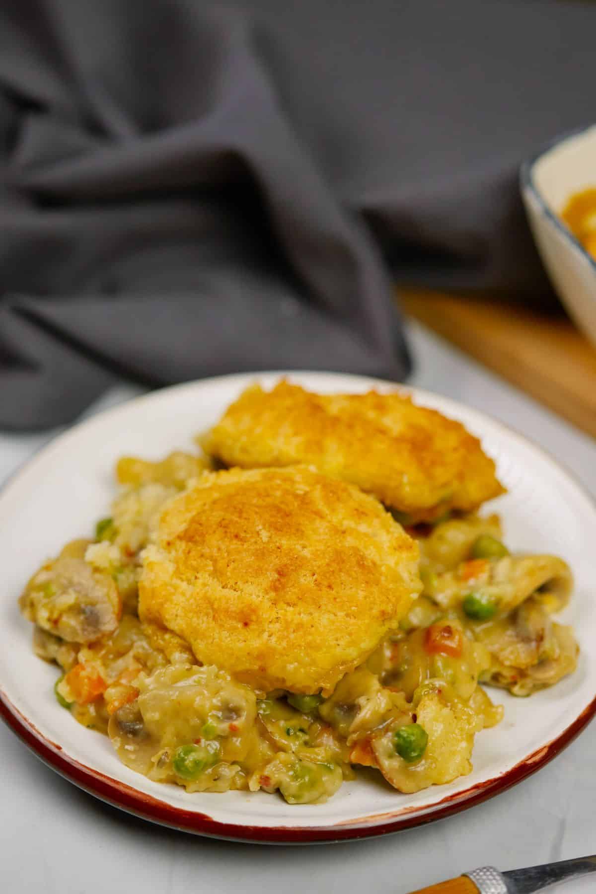 white plate with vegetable pot pie topped with biscuits 