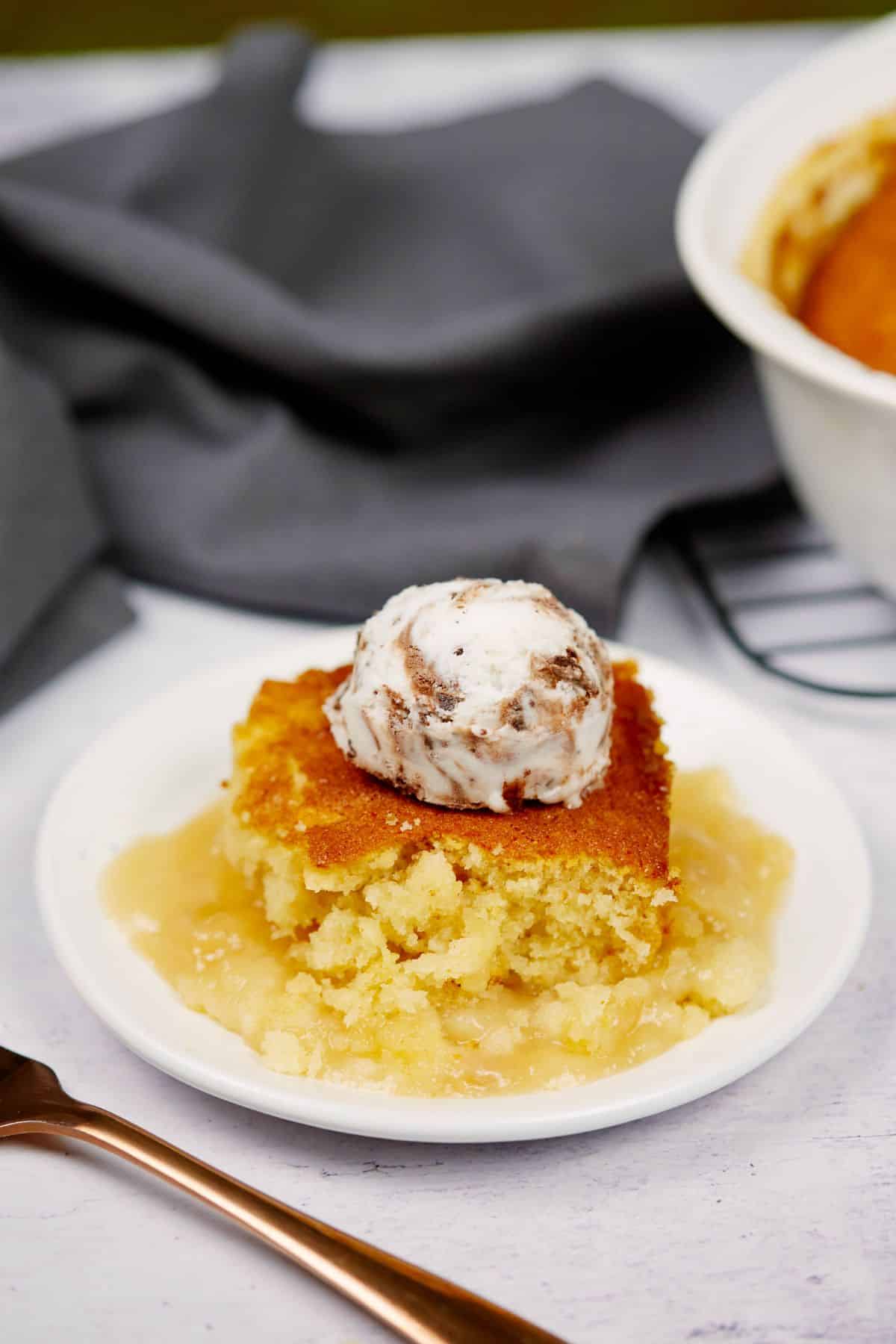 round white plate holding serving of butterscotch pudding casserole topped by scoop of ice cream