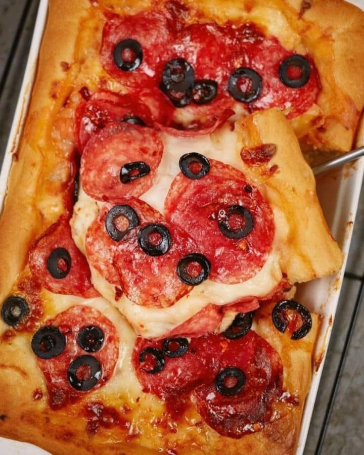 deep dish pizza topped with salami and olives in baking dish