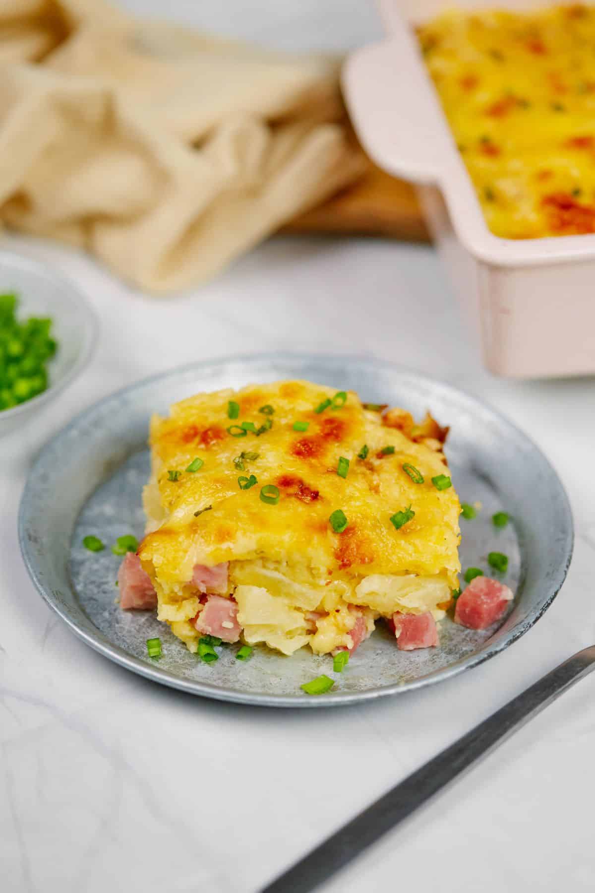 serving of pineapple casserole with ham on blue plate next to baking dish