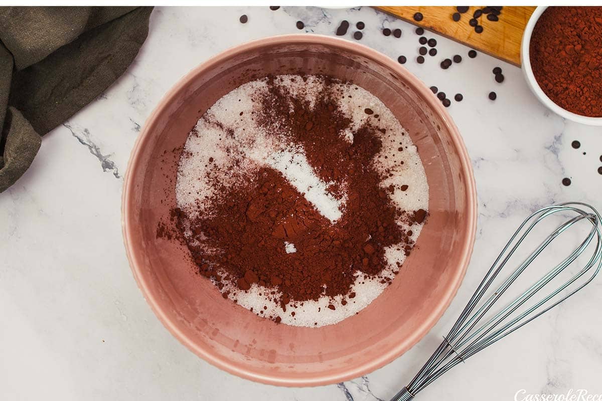 dry ingredients being added to a bowl to make chocolate cobbler