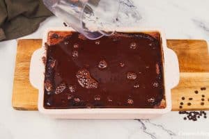 final step of adding chocolate drizzle to the top of chocolate cobbler prior to a final baking