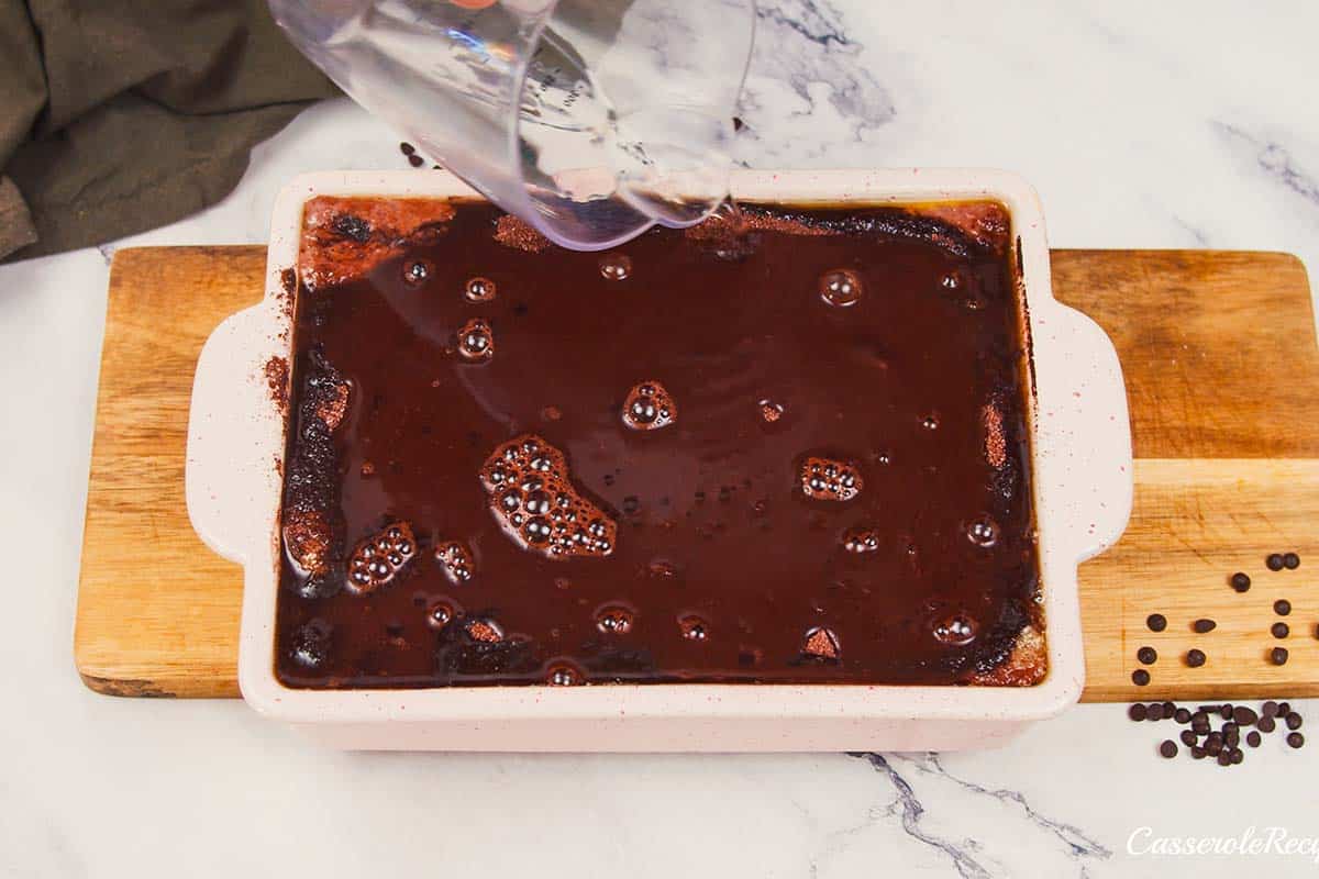 final step of adding chocolate drizzle to the top of chocolate cobbler prior to a final baking