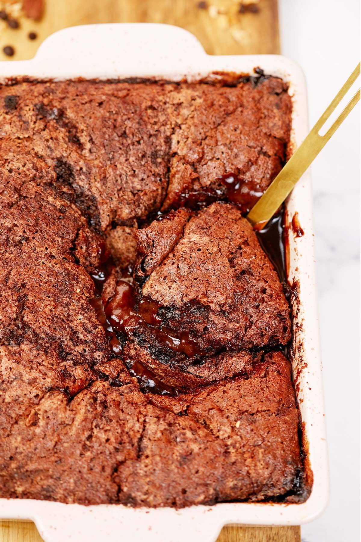 spoon scooping up a serving of chocolate cobbler from a baking dish
