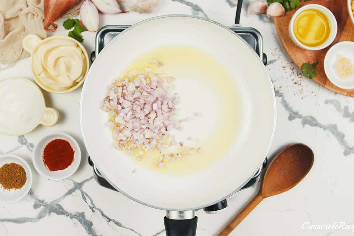 shallots being sauteed in a saucepan to make mexican street corn casserole