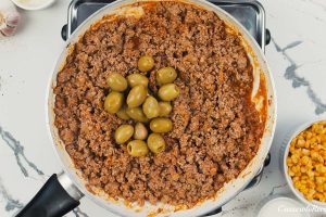 combining ingredients to make pastel de chocolo corn and beef casserole