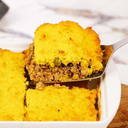 spatula lifting a serving of pastel de chocolo corn and beef casserole from a dish full of the meal