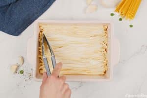 pasta being layered over cheese to make pastitsio greek beef pasta bake