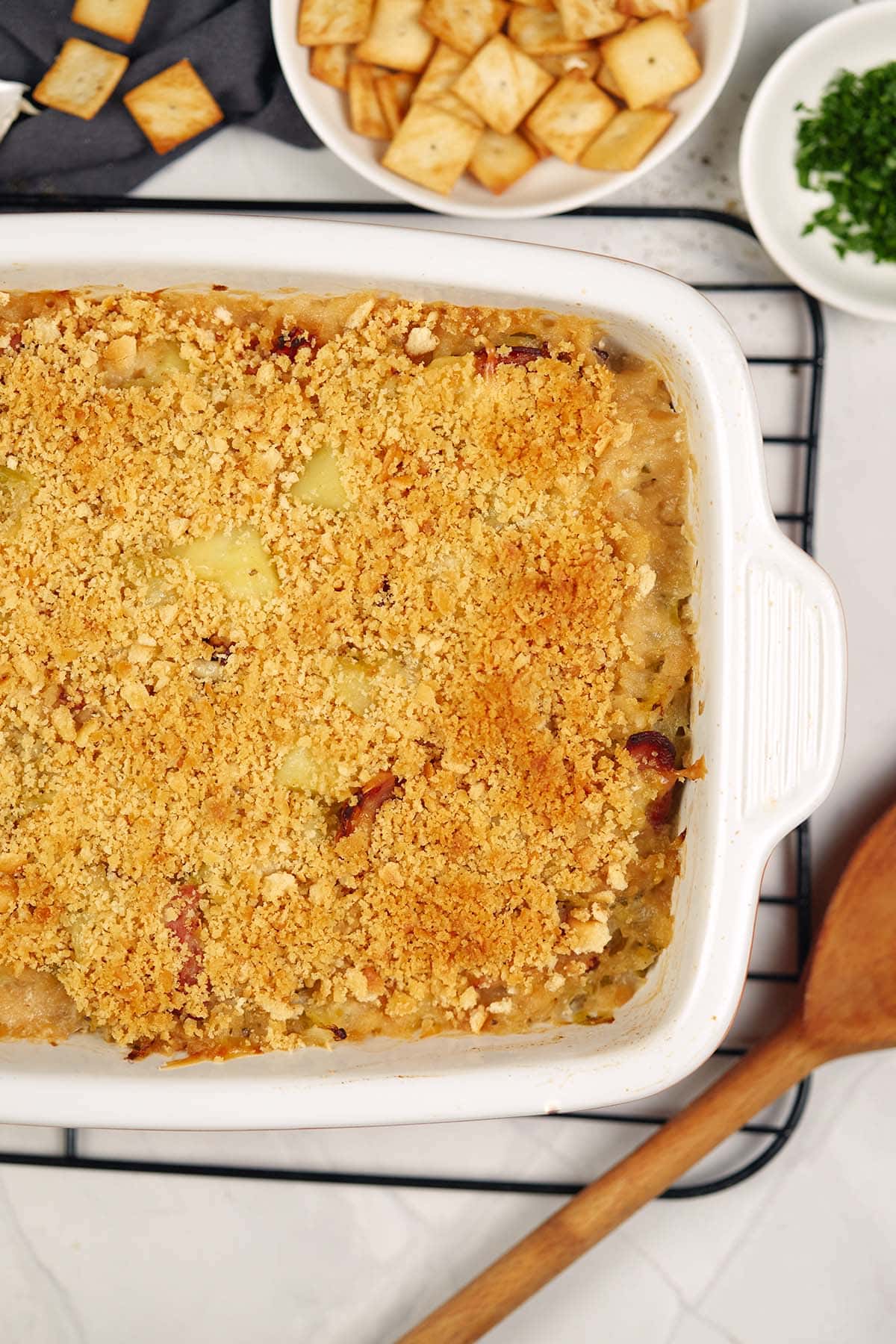 overhead view of a baking dish of polish cabbage, potato and bacon casserole on a table surrounded by extra ingredients