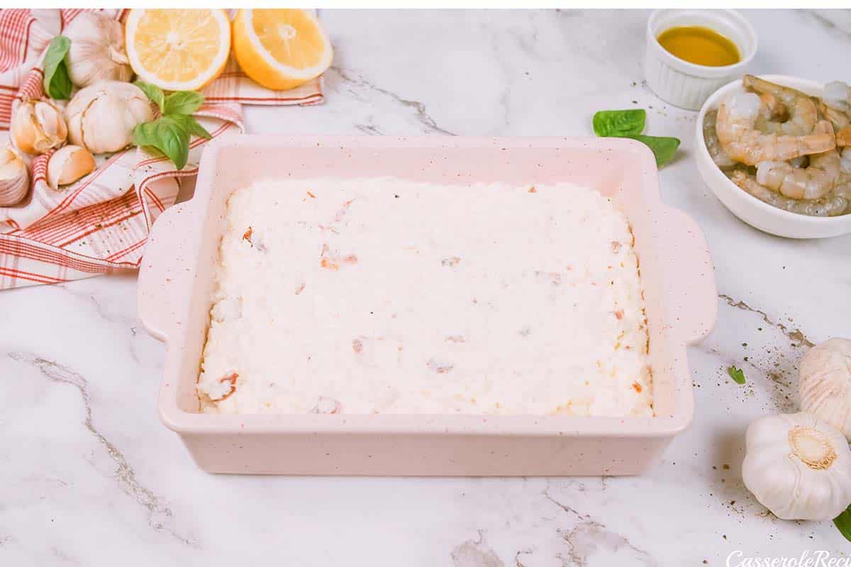 layering ingredients in a casserole dish to make shrimp and cauliflower bake