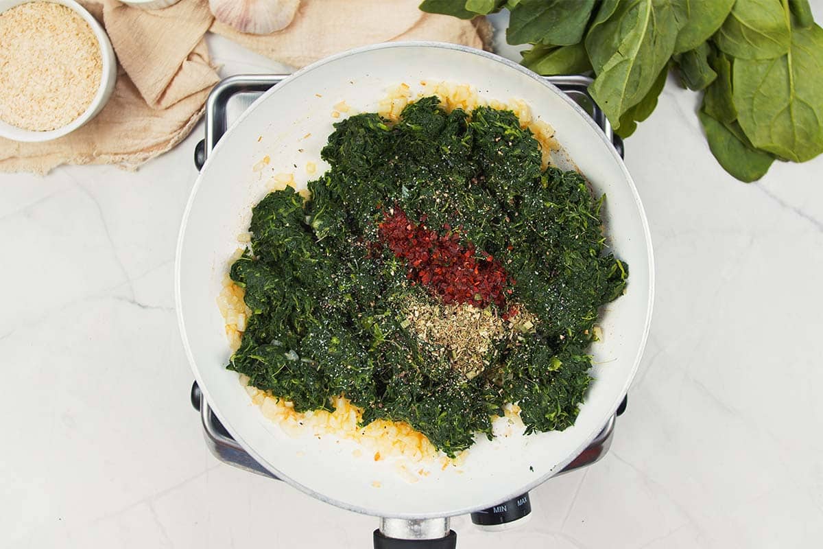 combining spinach with other ingredients to make the filling for spinach casserole with feta