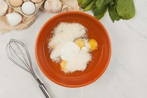 combining eggs and other ingredients to make spinach casserole with feta