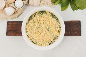 final step of making spinach casserole with feta by topping with breadcrumbs before baking