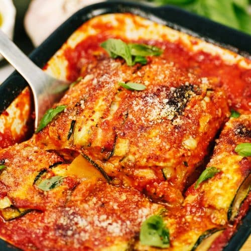 Zucchini Parmesan being lifted out of a casserole dish by a spatula