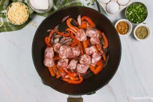 sausage and peppers being sautéed to make Cheesy Sausage Breakfast Casserole