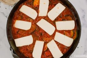 final step of topping the casserole with cheese prior to baking to make Tomato and Houllimi Bake