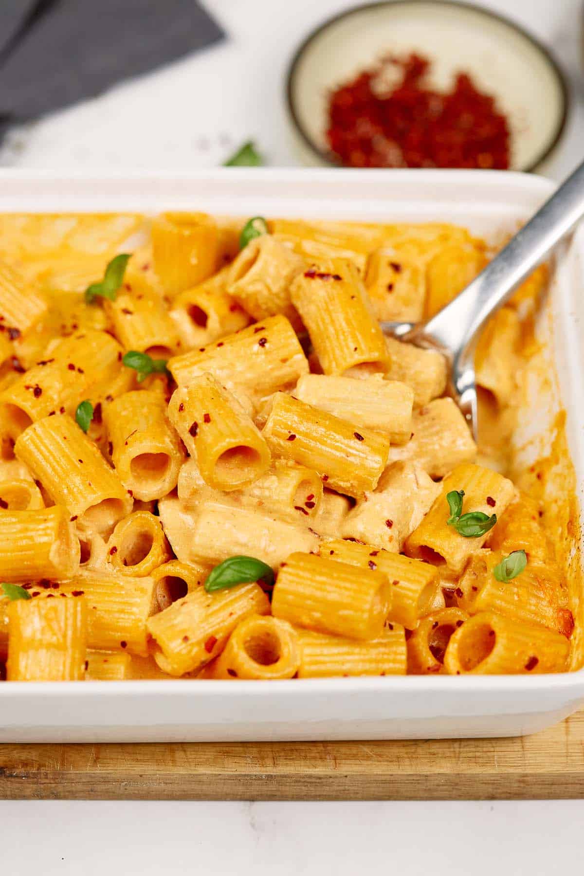 spoon scooping up a serving of baked feta pasta from a casserole dish
