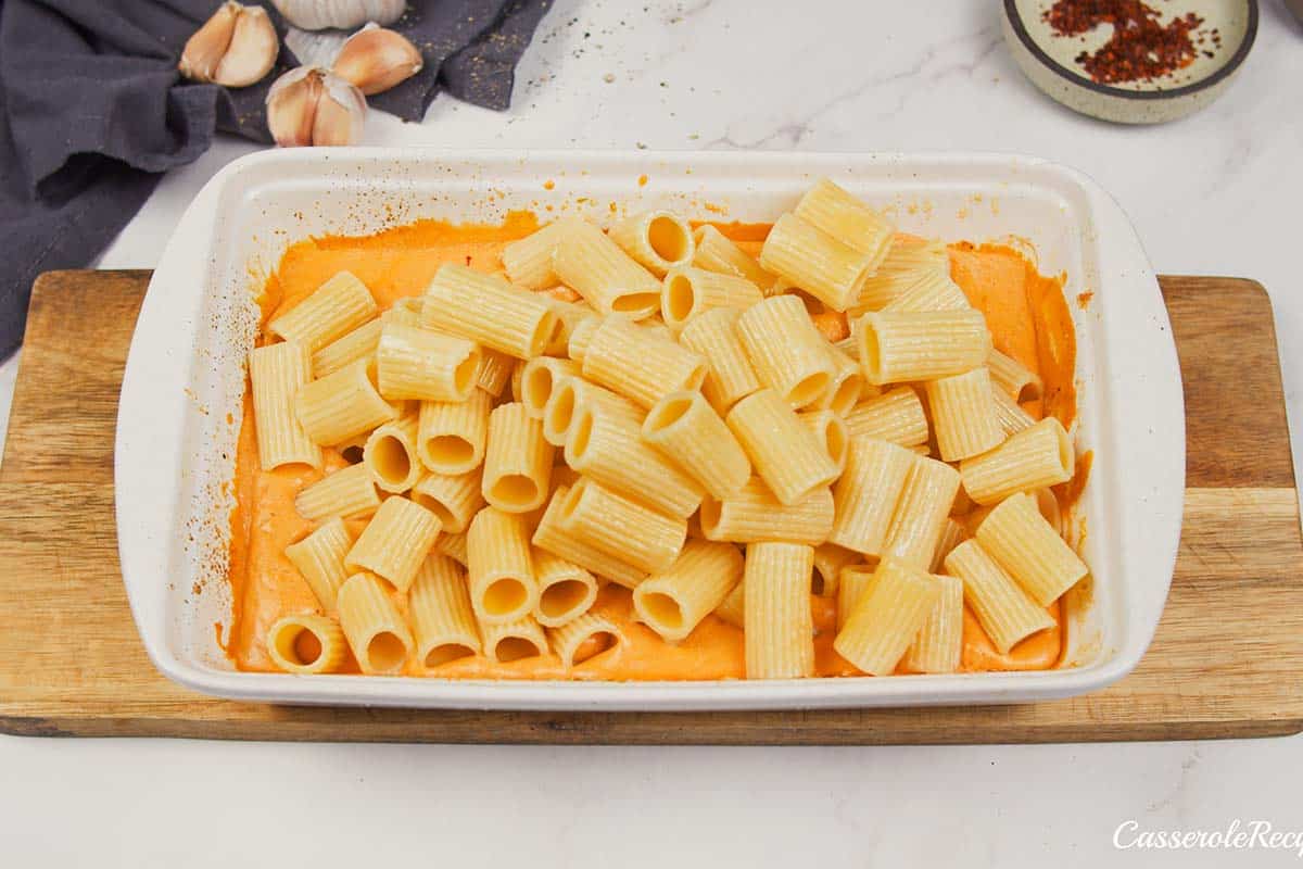 combining cooked pasta with other ingredients to make baked feta pasta