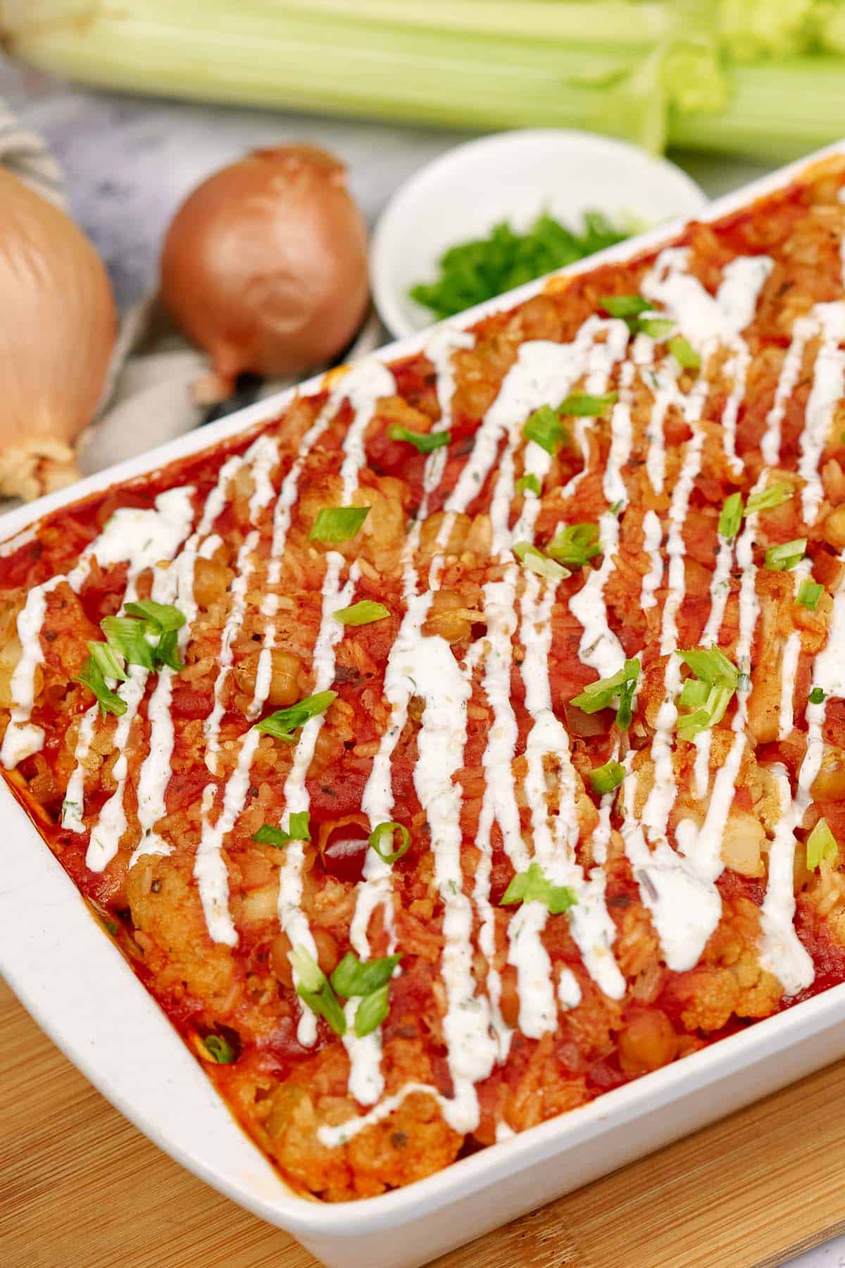 buffalo cauliflower and chickpea casserole in a baking dish on a table with extra ingredients