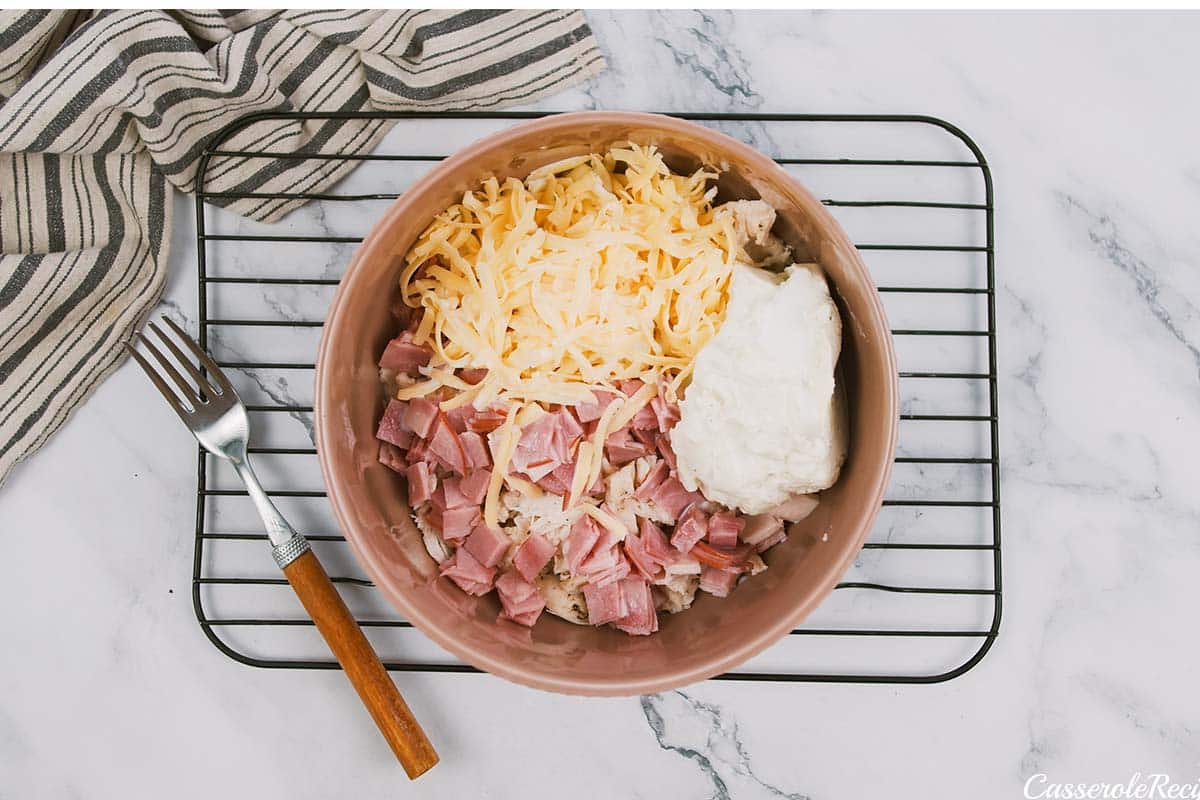 ingredients being combined in a bowl to make a chicken cordon bleu bubble-up bake