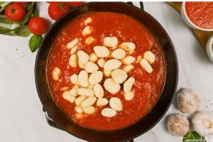 adding gnocchi to sauce to make chorizo gnocchi bake