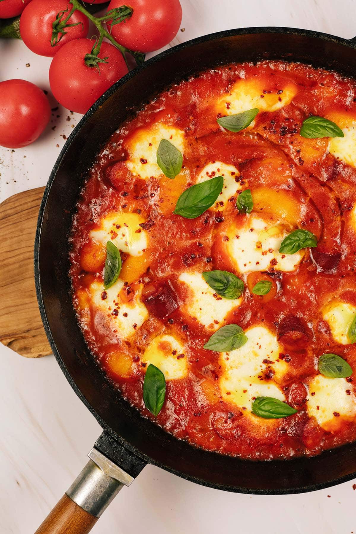 overhead view of chorizo gnocchi bake in a casserole dish on a table with ingredients