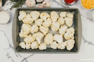 cauliflower florets on a baking pan to prepare it for creamy cauliflower casserole