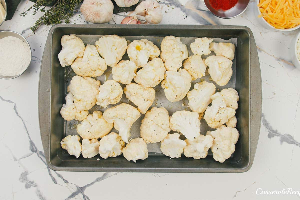 cauliflower florets on a baking pan to prepare it for creamy cauliflower casserole
