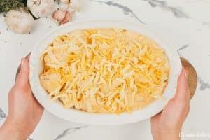 final step of covering the creamy cauliflower casserole with cheese prior to baking