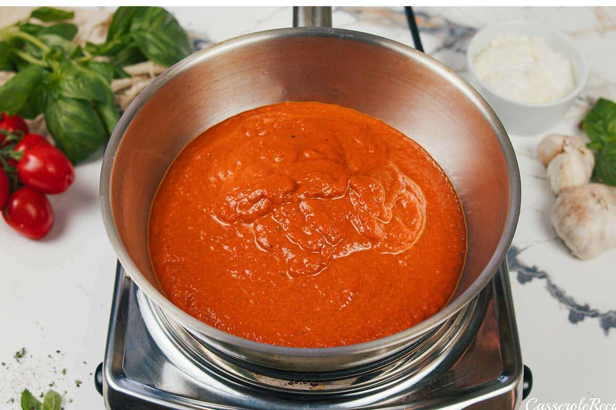 simmering sauce to make creamy sun-dried tomato and roasted red pepper casserole