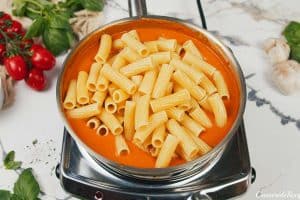 adding pasta to mixture to make creamy sun-dried tomato and roasted red pepper casserole