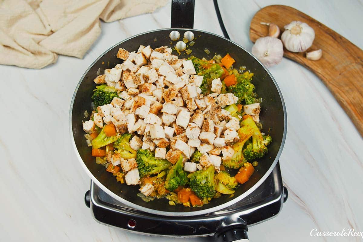 ingredients being sautéed to make curried chicken and grits casserole