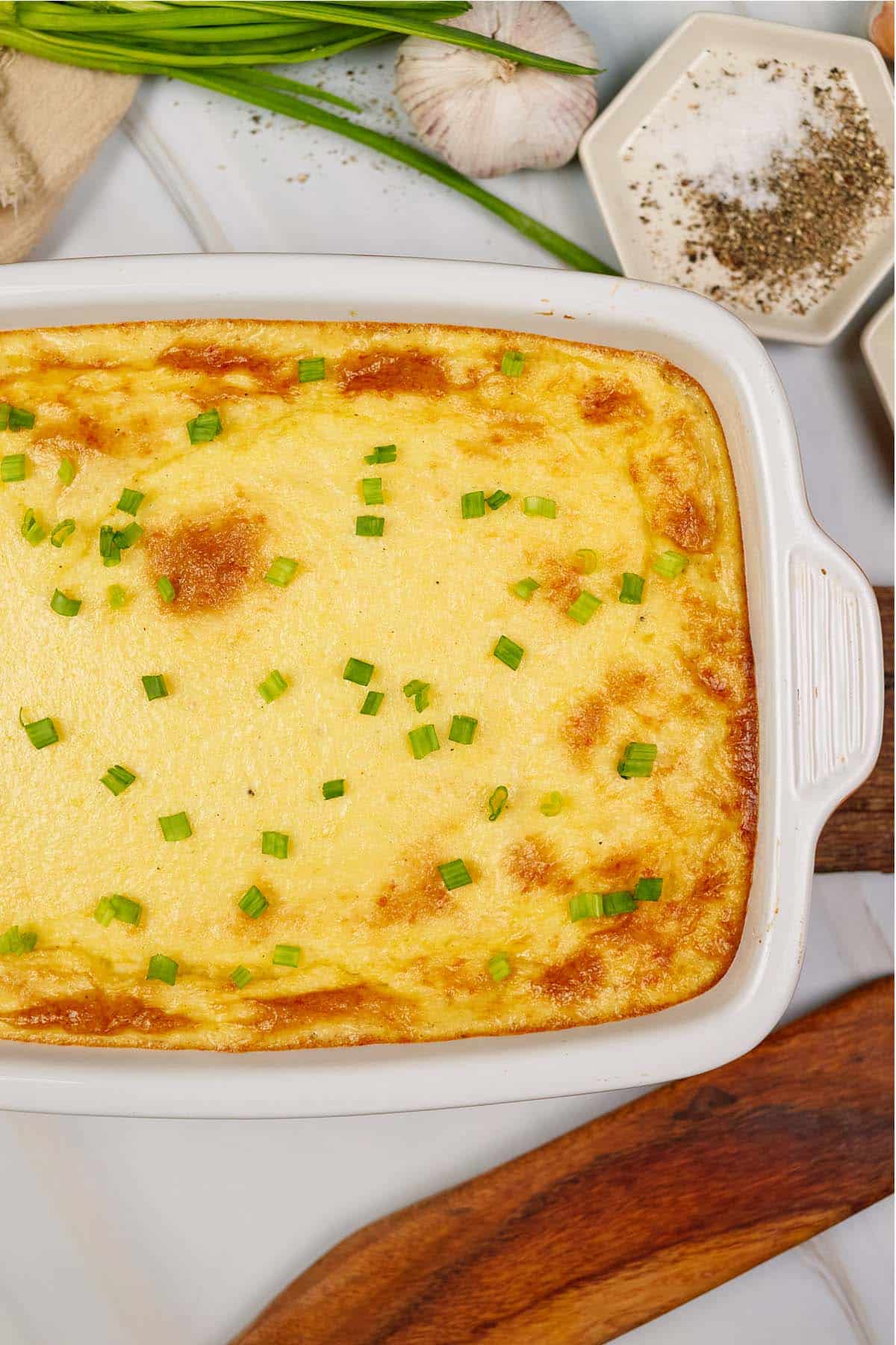 casserole dish of curried chicken and grits casserole on a table surrounded by other ingredients