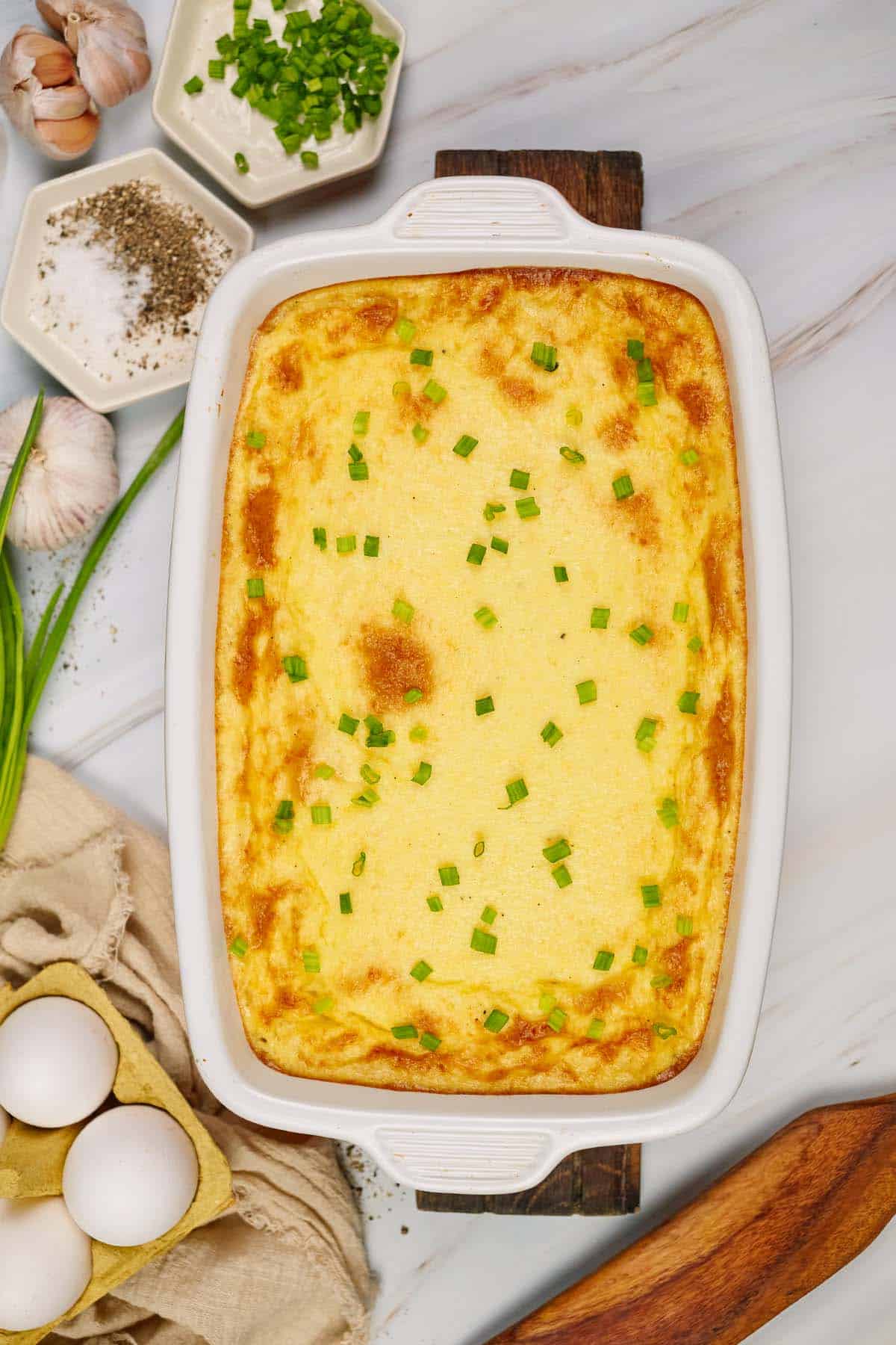 baking dish of curried chicken and grits casserole on a table with other ingredients