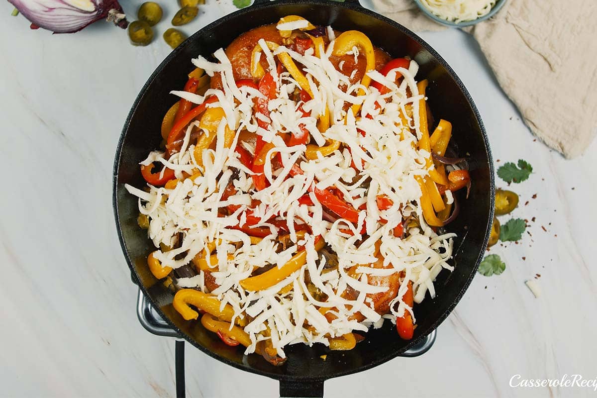 final step of making fajita chicken bake by topping with cheese prior to baking