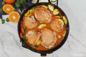 chicken added to the cast iron pan to make moroccan chicken casserole