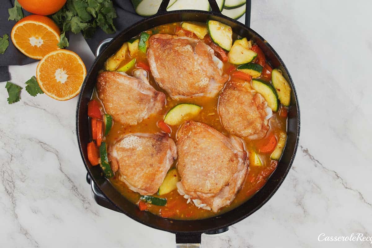 chicken added to the cast iron pan to make moroccan chicken casserole