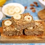 squares of peanut butter banana baked oatmeal on a serving board with other ingredients surrounding