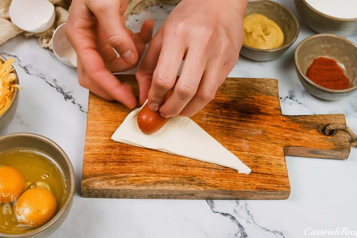 wrapping sausage in a puff pastry to make pigs in a blanket breakfast casserole