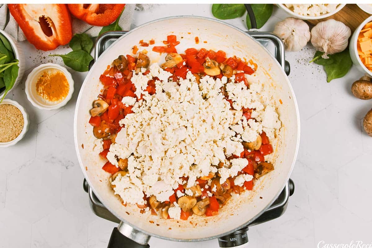 adding an ingredient to the mixture to make scrambled tofu casserole