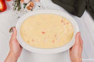 final step of putting the filling in a baking dish to make shrimp and grits bake prior to baking