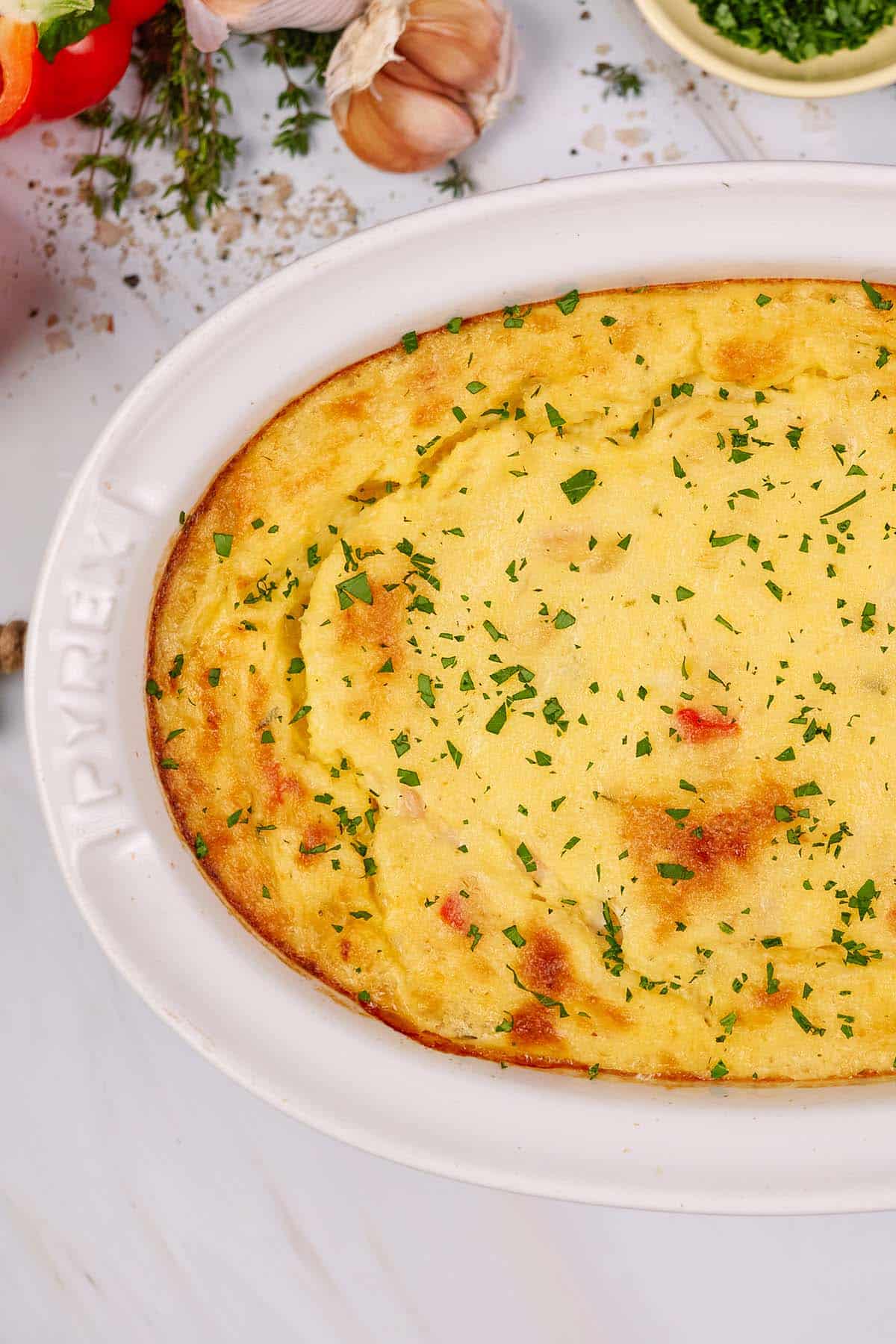 baking dish of shrimp and grits bake on a table with other ingredients