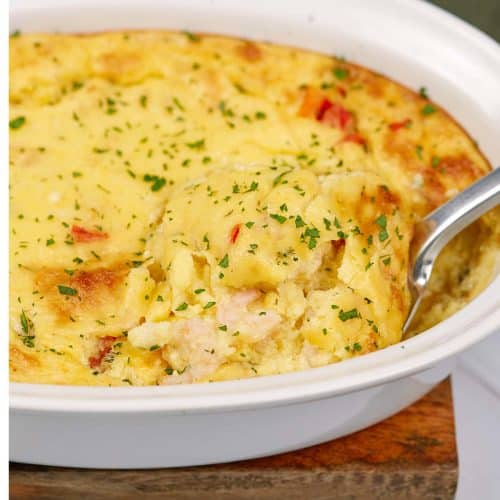 spatula scooping up a serving of shrimp and grits bake from a casserole dish