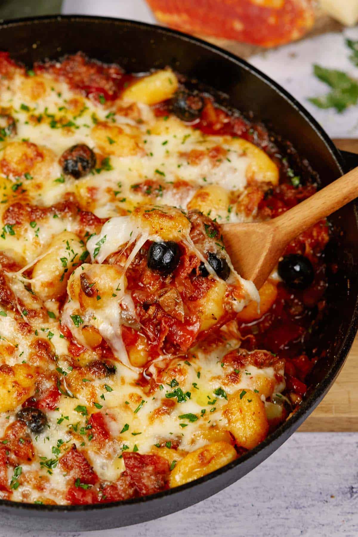 spoon scooping out a serving of supreme pizza gnocchi from a casserole dish